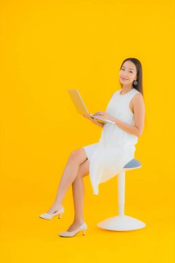 Sarı izole edilmiş arka planda bilgisayarlı güzel Asyalı kadın portresi.