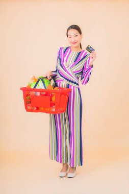 Marketten aldığı alışveriş sepetiyle güzel bir Asyalı kadının portresi. Renkli, izole arka plan.