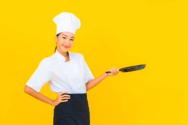 Sarı izole arka planda siyah şapkalı güzel Asyalı şef kadın portresi.
