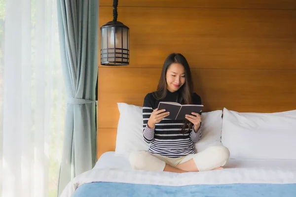 Portrait young asian woman read book in bedroom interior