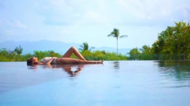 Güzel, genç Asyalı bir kadının dinlenme, dinlenme, deniz kenarında yüzme havuzu, tatil için deniz kenarında yüzme görüntüsü.