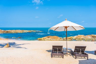 Güzel tropikal sahil denizi, şemsiyesi ve sandalyesi ile beyaz bulut ve mavi gökyüzü tatil seyahati için