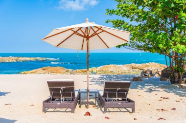 Güzel tropikal sahil denizi, şemsiyesi ve sandalyesi ile beyaz bulut ve mavi gökyüzü tatil seyahati için