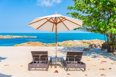 Güzel tropikal sahil denizi, şemsiyesi ve sandalyesi ile beyaz bulut ve mavi gökyüzü tatil seyahati için