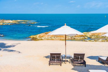 Güzel tropikal sahil denizi, şemsiyesi ve sandalyesi ile beyaz bulut ve mavi gökyüzü tatil seyahati için