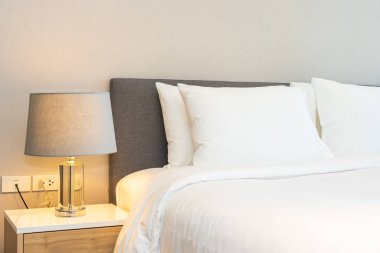 Yatak odasının iç dekorasyonuna beyaz yastık ve battaniye. İçinde lamba var.