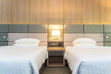 Yatak odasının içinde lamba süslemesi olan beyaz rahat yastık ve battaniye.