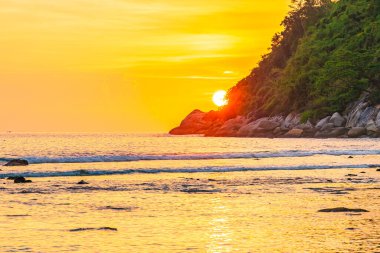 Sahildeki okyanusun etrafındaki dağda güzel bir gün batımı ve doğa gezisi için kaya.