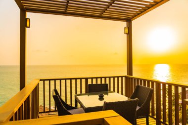 Gün batımında ya da gün doğumunda okyanus çevresinde sandalyeli güzel bir bahçe.