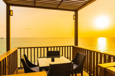 Gün batımında ya da gün doğumunda okyanus çevresinde sandalyeli güzel bir bahçe.