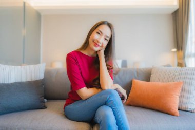 Güzel bir Asyalı kadın portresi. Yatak odasındaki kanepede rahatla. Gülümse.