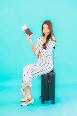 Güzel Asyalı bir kadının portresi. Bavul pasaportu ve biniş kartı mavi arka planda seyahat için hazır.