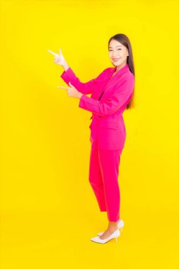 Güzel bir Asyalı kadın sarı arka planda gülümsüyor.