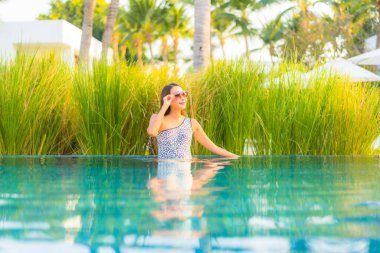 Güzel bir Asyalı kadın portresi. Rahatlayın, gülümseyin. Tatil için oteldeki yüzme havuzunun keyfini çıkarın.