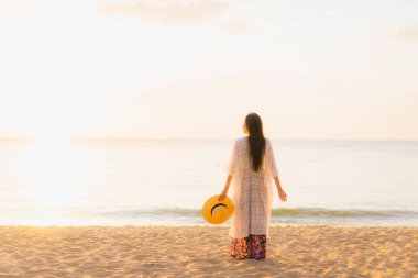 Güzel Asyalı genç kadınların portresi mutlu bir gülümseme. Gün batımında ya da gün doğumunda deniz okyanusunda rahatlayın. Seyahat için.