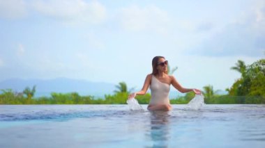 Güzel, genç Asyalı bir kadının dinlenme, dinlenme, deniz kenarında yüzme havuzu, tatil için deniz kenarında yüzme görüntüsü.