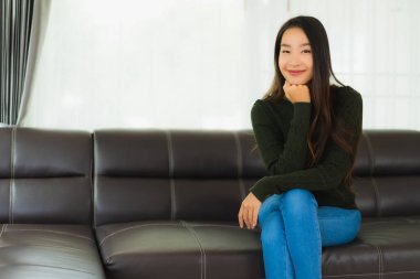 Güzel bir portre. Genç Asyalı kadın. Oturma odasındaki kanepede rahatla.