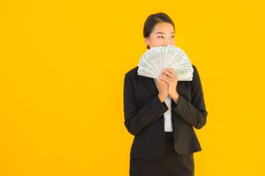 Sarıya boyanmış arka planda bir sürü nakit parası olan güzel bir Asyalı kadın portresi.