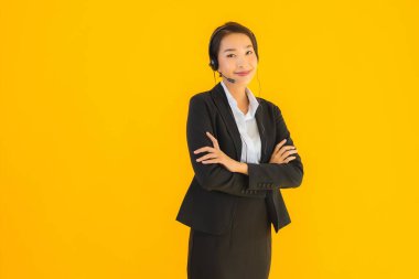 Portre güzel genç Asyalı kadın kulaklık ya da çağrı merkezi için kulaklık ya da tele pazarlama sarı izole arka planda.