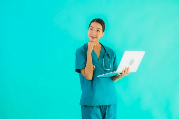 Portrait beautiful young asian doctor woman with laptop or computer on blue isolated background