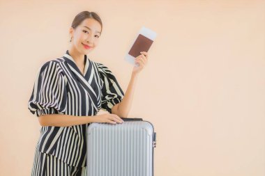 Çantalı güzel bir Asyalı kadın. Pasaportu ve uçak bileti kahverengi arka planda.