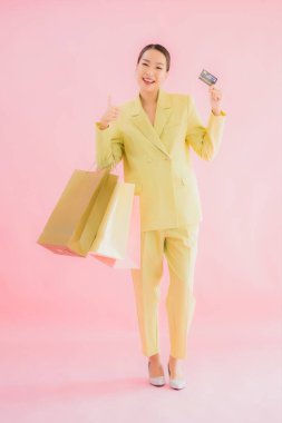 Renkli arka planda alışveriş çantası taşıyan güzel Asyalı iş kadını portresi.