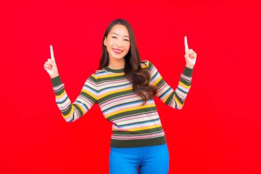 Güzel bir Asyalı kadının portresi. Kırmızı izole edilmiş arka planda hareketli gülümsüyor.