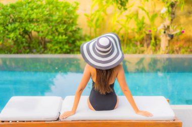 Güzel bir Asyalı kadının portresi tatil için yüzme havuzunda rahatlıyor.
