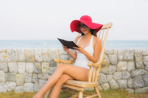 Portrait young asian woman read book around beach sea ocean in travel vacation