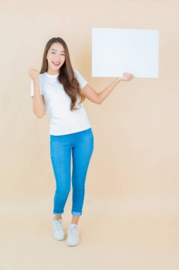 Güzel bir Asyalı kadın portresi. Krem arka planda boş beyaz ilan panosu kağıdı gösteriyor.