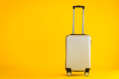 Gri renkli valiz ya da bagaj çantası kullanımı sarı izole arka planda seyahat ve boş zaman için