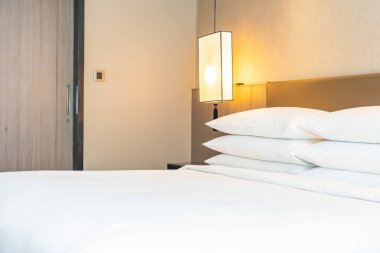 Yatak odasının iç kısmında beyaz rahat yastık ve battaniye süslemesi.