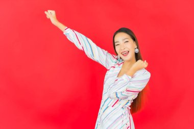 Güzel bir Asyalı kadının portresi kırmızı arka planda birçok hareketle gülümsüyor.