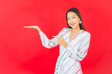 Güzel bir Asyalı kadının portresi kırmızı arka planda birçok hareketle gülümsüyor.