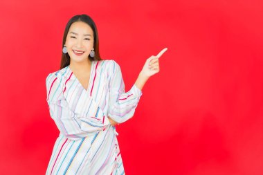 Güzel bir Asyalı kadının portresi kırmızı arka planda birçok hareketle gülümsüyor.