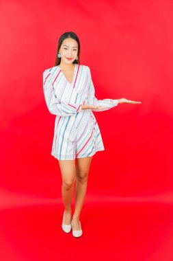 Güzel bir Asyalı kadının portresi kırmızı arka planda birçok hareketle gülümsüyor.