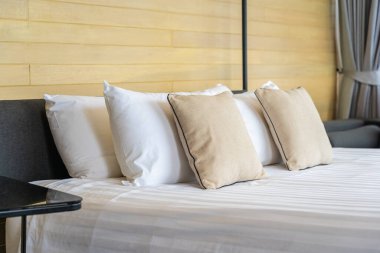 Otel odasındaki yatak odasının iç dekorasyonunda beyaz rahat yastık.