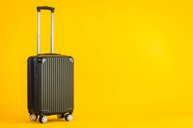 Sarı izole arka planda siyah renkli valiz ya da bagaj çantası kullanımı