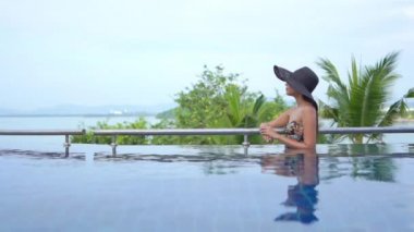 Güzel, genç Asyalı bir kadının dinlenme, dinlenme, deniz kenarında yüzme havuzu, tatil için deniz kenarında yüzme görüntüsü.