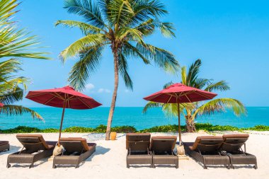 Güzel tropikal deniz okyanusu, şemsiyesi ve sandalyesi ile mavi gökyüzünde hindistan cevizi palmiyesinin etrafında tatil için