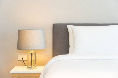 Yatak odasının iç dekorasyonuna beyaz yastık ve battaniye. İçinde lamba var.