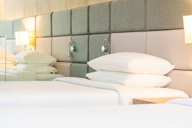 Yatak odasının içinde lamba süslemesi olan beyaz rahat yastık ve battaniye.