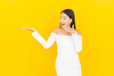 Portre güzel genç iş kadını gülümseyen ve eylem sarı arka planlı Asyalı kadın