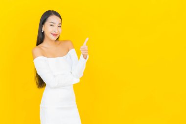 Portre güzel genç iş kadını gülümseyen ve eylem sarı arka planlı Asyalı kadın