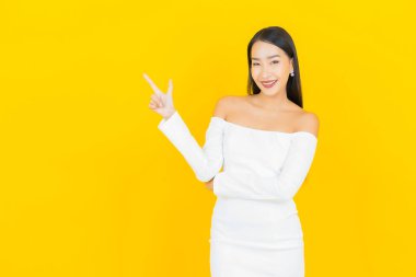 Portre güzel genç iş kadını gülümseyen ve eylem sarı arka planlı Asyalı kadın