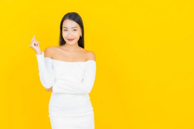 Portre güzel genç iş kadını gülümseyen ve eylem sarı arka planlı Asyalı kadın