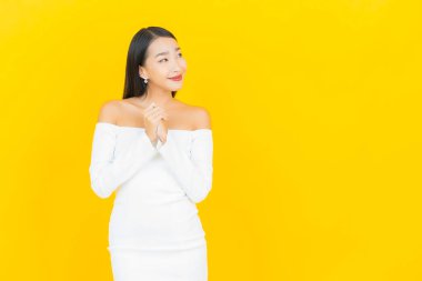 Portre güzel genç iş kadını gülümseyen ve eylem sarı arka planlı Asyalı kadın