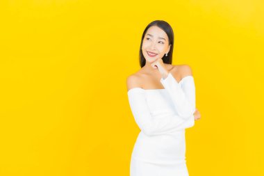 Portre güzel genç iş kadını gülümseyen ve eylem sarı arka planlı Asyalı kadın