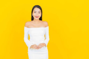 Portre güzel genç iş kadını gülümseyen ve eylem sarı arka planlı Asyalı kadın