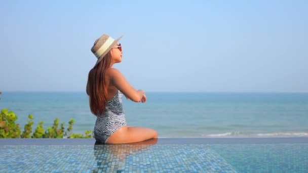 美しい若いアジアの女性の映像休日の休暇のために海のビーチの海の近くの屋外スイミングプールの周りの笑顔のレジャーをリラックス — ストック動画